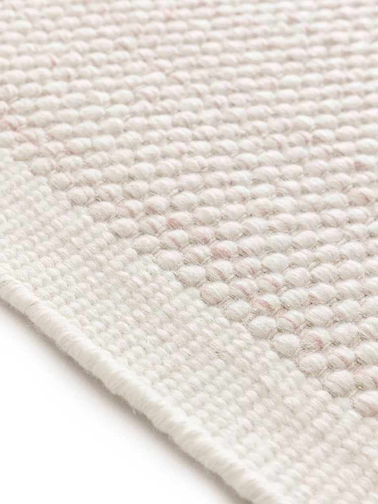 Tapis scandinave tressé enfant crème et corail en laine 90x130 cm